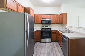 A kitchen with a refrigerator, oven, and microwave.